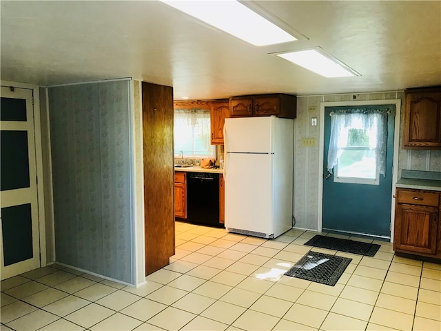 kitchen featuring black dishwasher, sink, light tile patterned floors, and white refrigerator