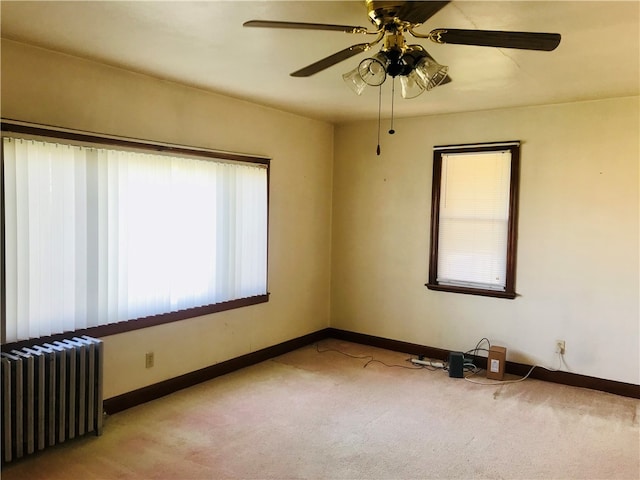 carpeted empty room featuring radiator and ceiling fan