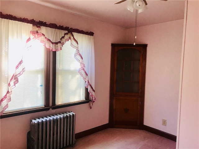 spare room with radiator, ceiling fan, and light colored carpet