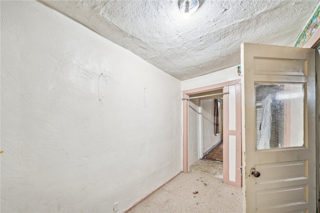 corridor featuring light carpet and a textured ceiling