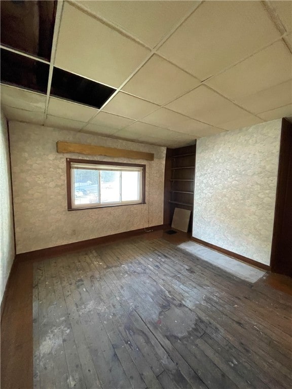 unfurnished room with a drop ceiling and wood-type flooring