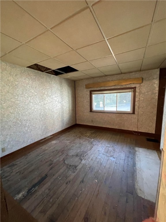 unfurnished room with a drop ceiling and hardwood / wood-style flooring