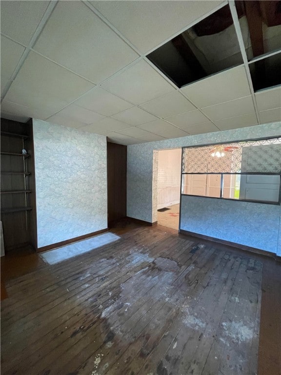 empty room featuring a drop ceiling and dark wood-type flooring