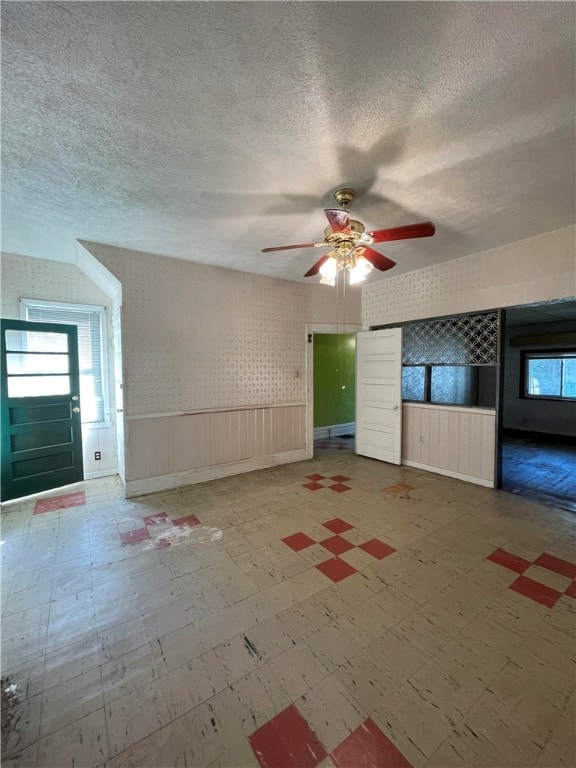 unfurnished living room with a textured ceiling and ceiling fan