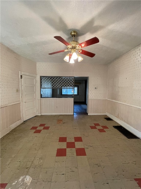 empty room with a textured ceiling and ceiling fan