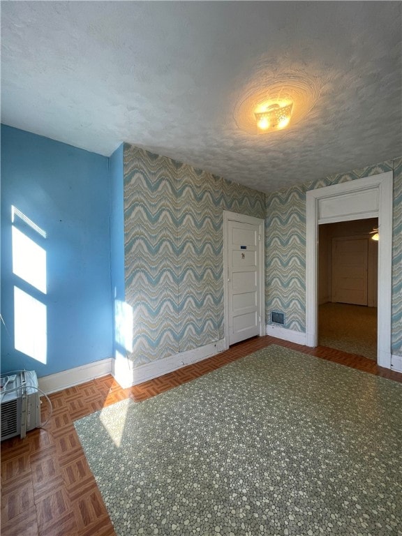 unfurnished room with a textured ceiling and parquet floors