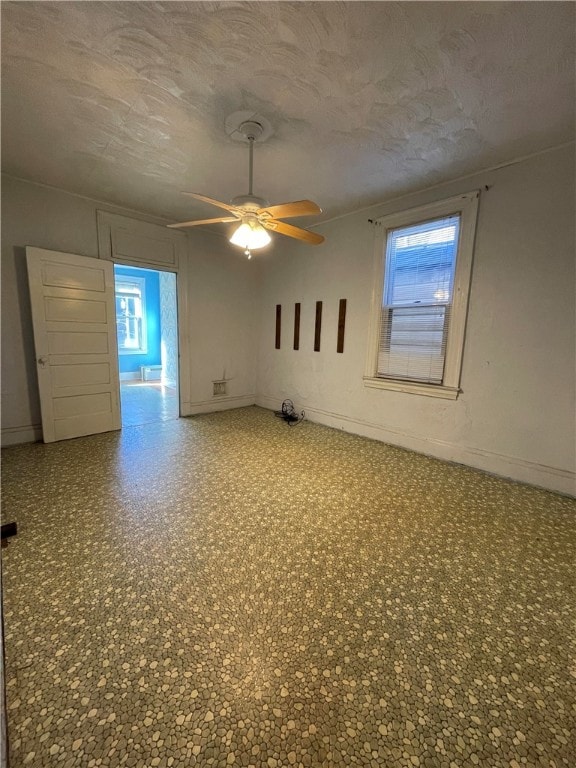 empty room with a textured ceiling and ceiling fan