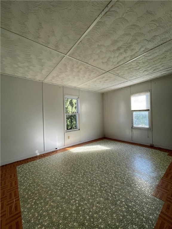 empty room featuring dark parquet floors and a wealth of natural light