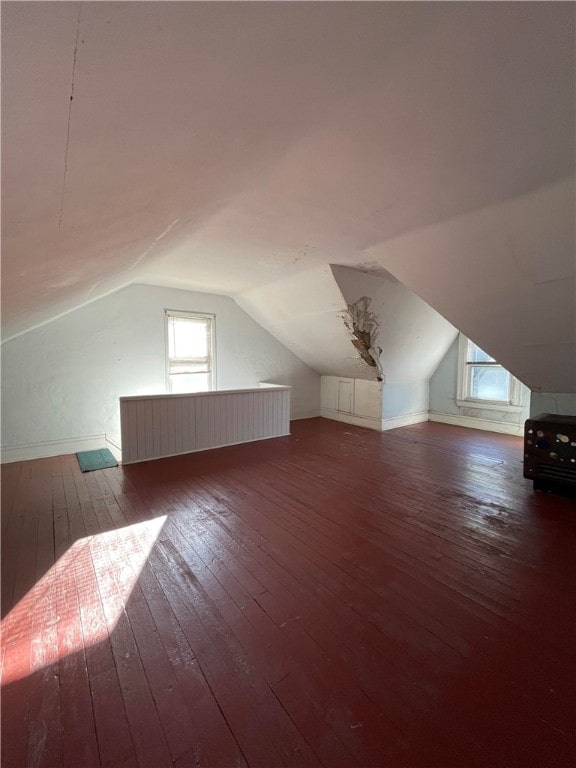 additional living space with dark wood-type flooring and vaulted ceiling