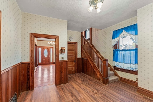 stairs featuring hardwood / wood-style flooring, a textured ceiling, and an inviting chandelier