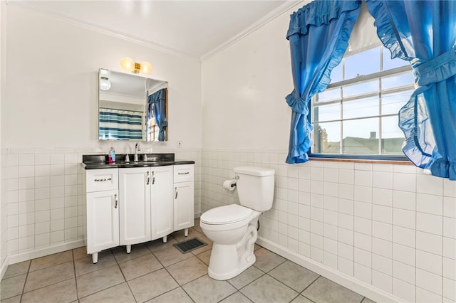 bathroom with tile patterned flooring, crown molding, toilet, vanity, and tile walls