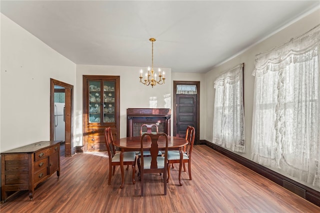 dining space with dark hardwood / wood-style floors and an inviting chandelier