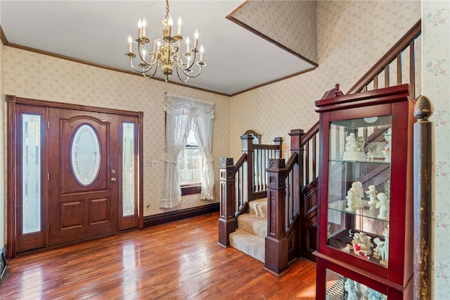 foyer entrance with a notable chandelier, dark hardwood / wood-style floors, and ornamental molding