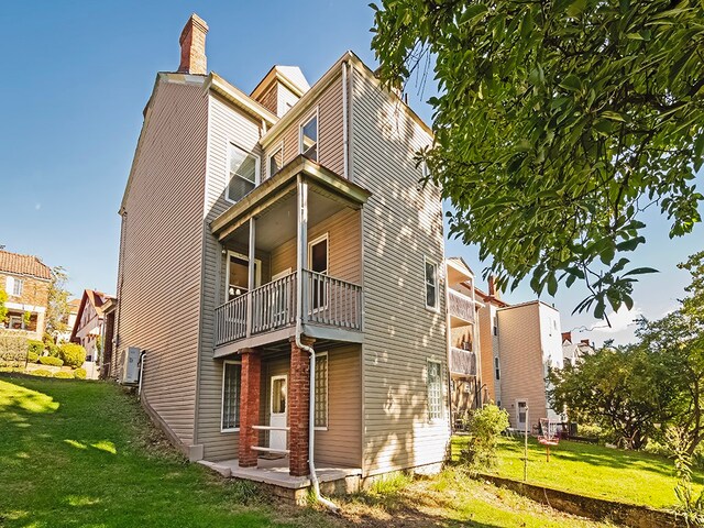 back of house featuring a yard and a balcony