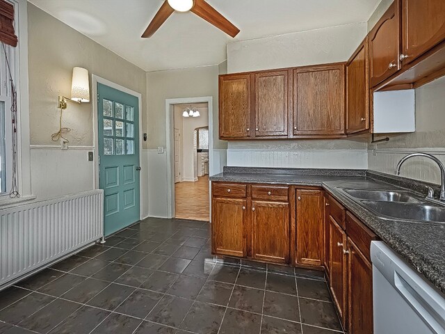 kitchen featuring dark tile patterned floors, dishwasher, sink, radiator heating unit, and ceiling fan with notable chandelier