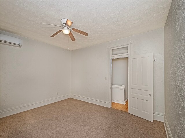 unfurnished bedroom with light carpet, a wall unit AC, a textured ceiling, and ceiling fan