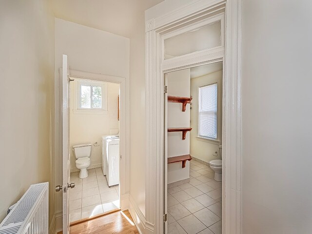 bathroom with radiator, toilet, tile patterned floors, and washer / dryer