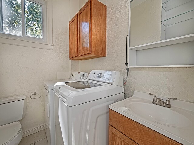 laundry area with sink, independent washer and dryer, and light tile patterned floors