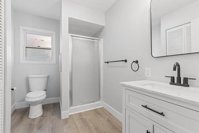 bathroom with vanity, hardwood / wood-style floors, a shower with shower door, and toilet