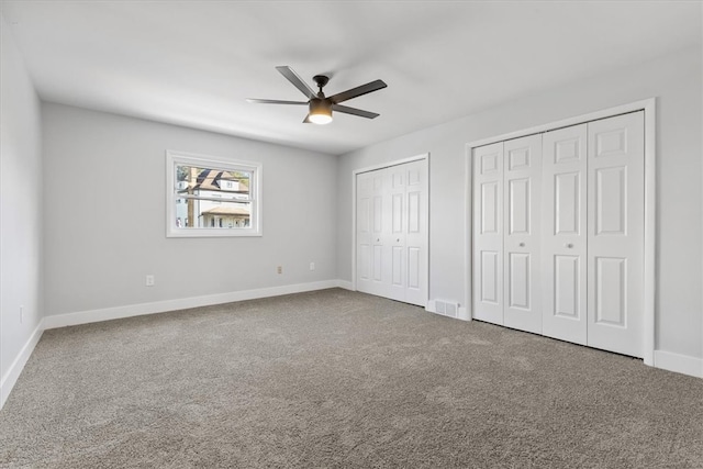 unfurnished bedroom featuring multiple closets, carpet, and ceiling fan