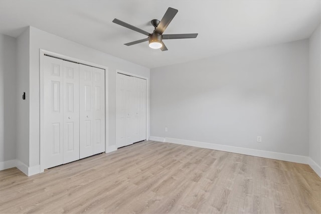 unfurnished bedroom with ceiling fan, multiple closets, and light hardwood / wood-style flooring