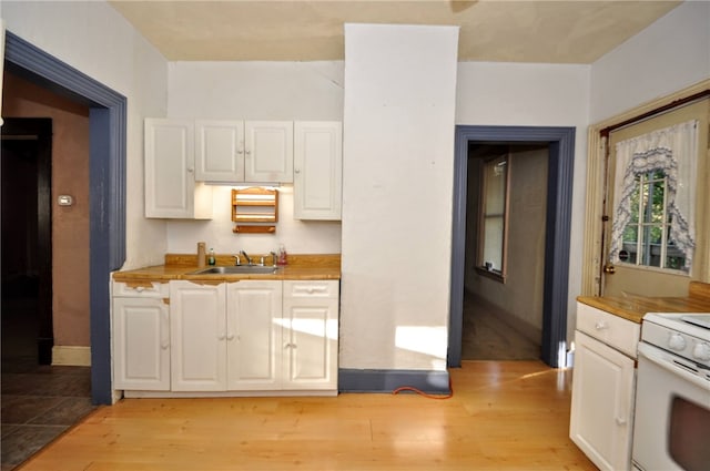 kitchen with white cabinets, wooden counters, sink, and light wood-type flooring