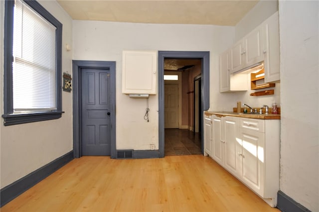 kitchen featuring white cabinetry, sink, and light wood-type flooring