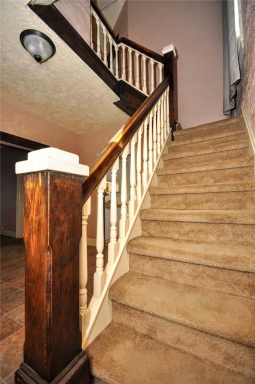 staircase featuring tile patterned floors and a textured ceiling