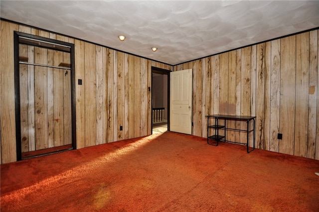 unfurnished bedroom featuring wooden walls and carpet flooring