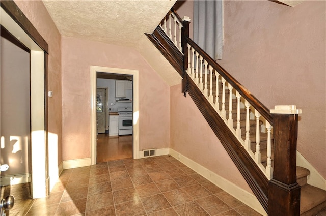 stairs featuring a textured ceiling