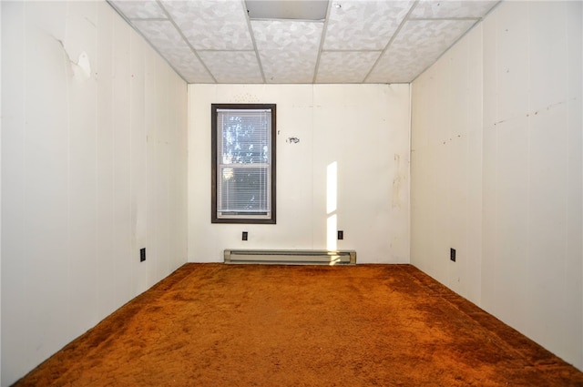 carpeted spare room featuring baseboard heating, a paneled ceiling, and wood walls