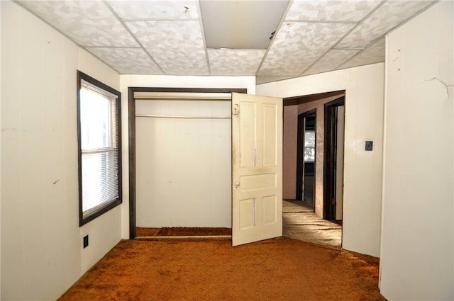 unfurnished bedroom with a closet, carpet, and a drop ceiling