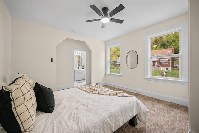 carpeted bedroom with ensuite bath and ceiling fan