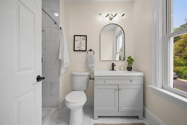 bathroom featuring vanity, a tile shower, and a healthy amount of sunlight