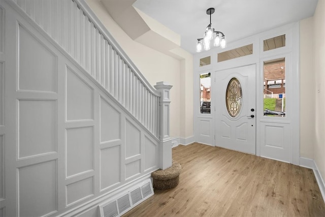 foyer with light hardwood / wood-style flooring and a notable chandelier