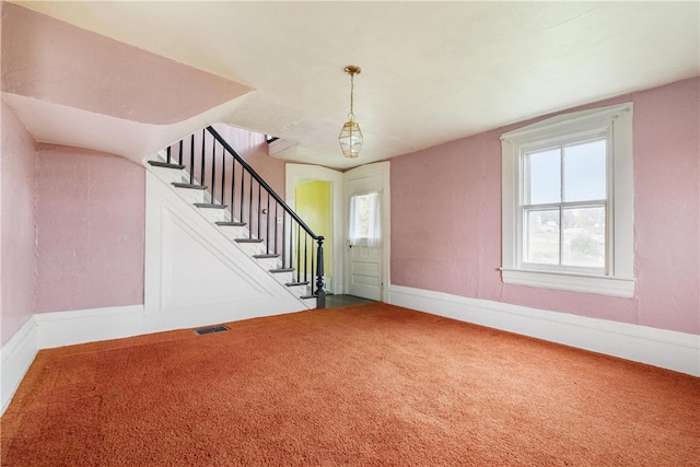 interior space featuring a wealth of natural light, a notable chandelier, and carpet flooring