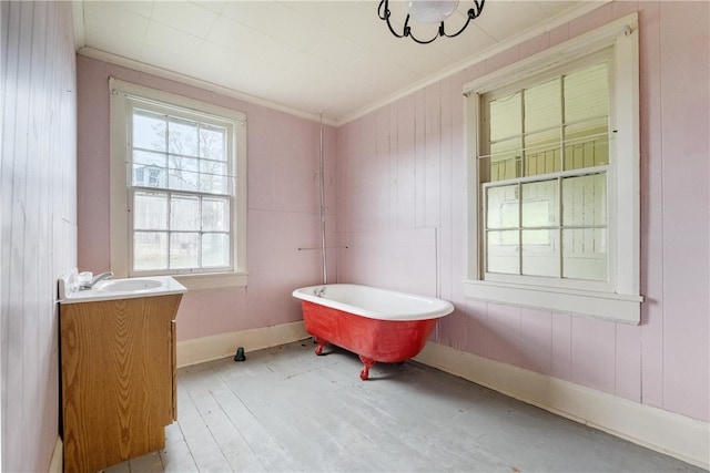 bathroom with wood-type flooring, ornamental molding, a washtub, vanity, and wooden walls