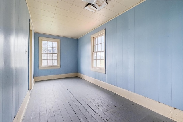 unfurnished room featuring light hardwood / wood-style flooring, wood walls, and plenty of natural light