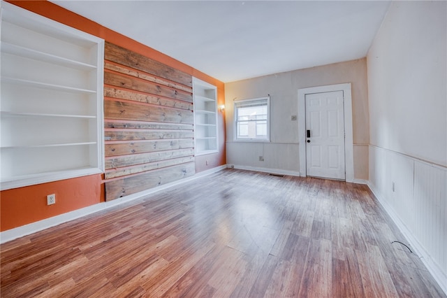 interior space featuring hardwood / wood-style flooring, built in features, and wood walls