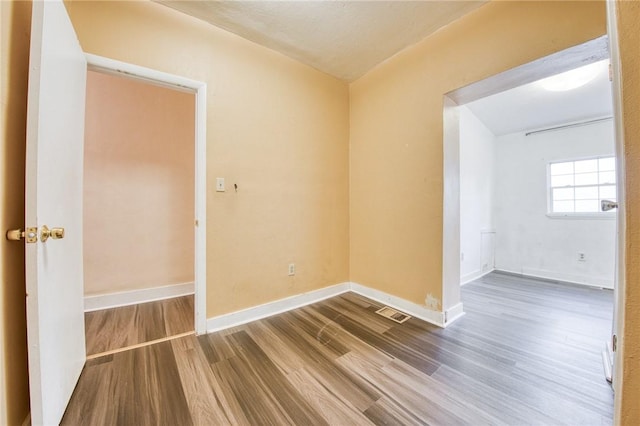 spare room with baseboards, visible vents, and wood finished floors