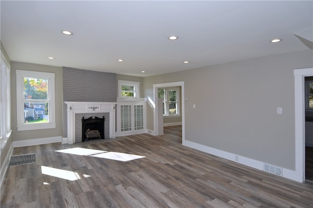 unfurnished living room with a wealth of natural light, a fireplace, and dark hardwood / wood-style floors