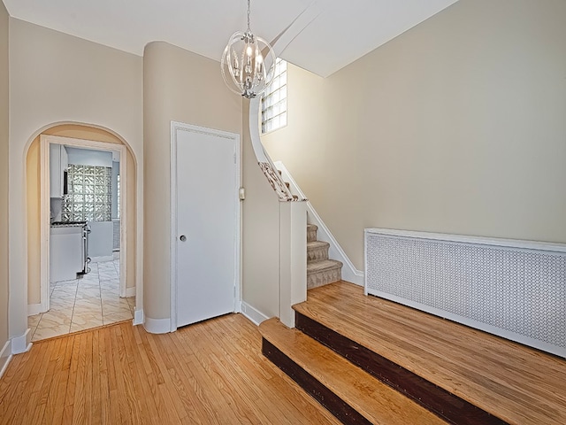 staircase with hardwood / wood-style floors and a chandelier