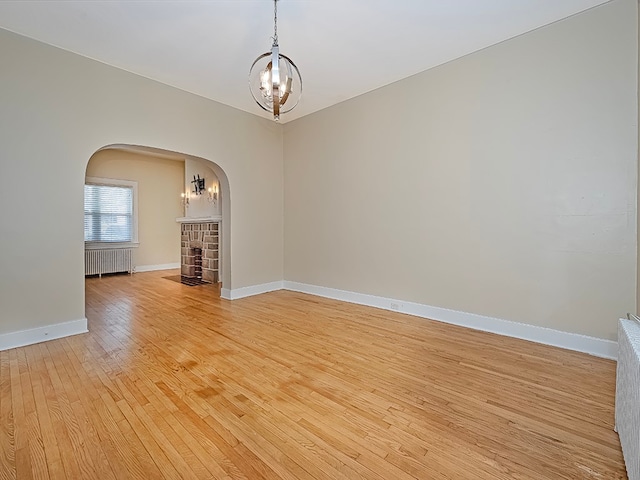 empty room featuring a notable chandelier, light hardwood / wood-style floors, and radiator