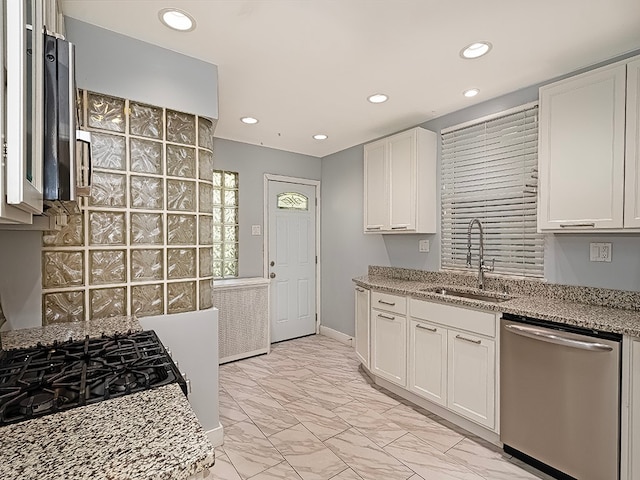 kitchen featuring light stone countertops, sink, stainless steel dishwasher, and white cabinets