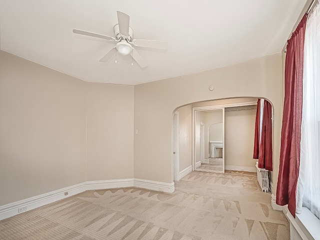 carpeted spare room featuring a fireplace and ceiling fan