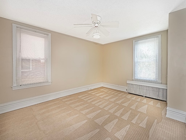 carpeted spare room featuring ceiling fan, a textured ceiling, and radiator heating unit