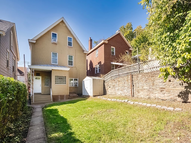 rear view of property with a storage shed and a lawn