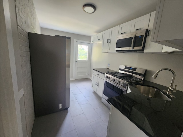 kitchen featuring light tile patterned flooring, white cabinetry, stainless steel appliances, and sink