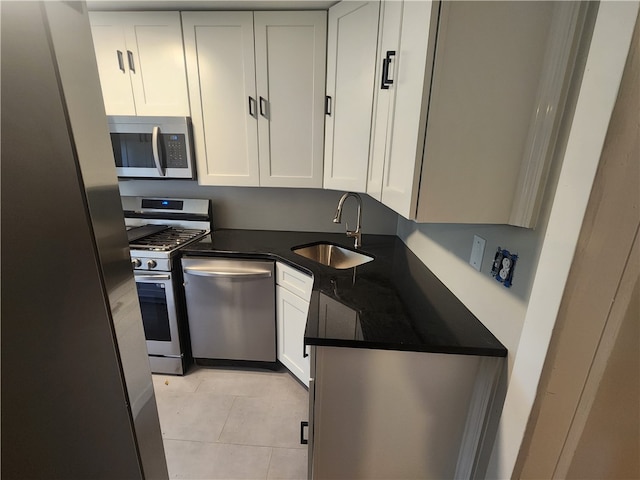 kitchen with sink, appliances with stainless steel finishes, white cabinets, and light tile patterned floors