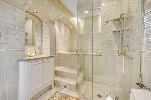 bathroom with vanity, tile patterned flooring, toilet, tile walls, and a shower with shower door